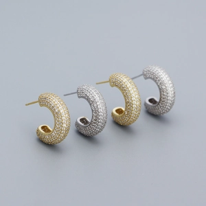 Close-up of gold and silver C-shaped earrings with full pavé cubic zirconia inlay