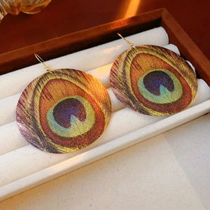 Detailed close-up of Bohemian peacock feather pattern earrings in a luxury jewelry box