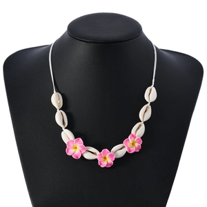 Détail du collier de style bohème en coquillage avec fleurs roses sur support blanc