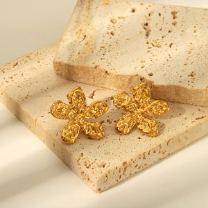 Détails de boucles d'oreilles fleur dorées avec texture martelée sur pierre