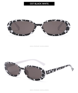 Detail view of oval sunglasses with black and white spotted frames and gray lenses