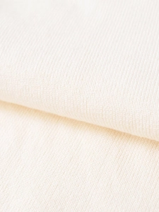 Dettaglio macro della maglia in pizzo crema con trama di perline per gonne midi