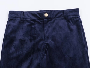 Close-up of navy blue velvet flared trousers featuring a detailed gold embossed button