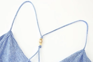 Detail of blue linen camisole strap featuring decorative wood and metal bead accents