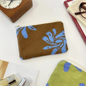 Flat lay of floral canvas zipper pouches with lifestyle accessories on white table