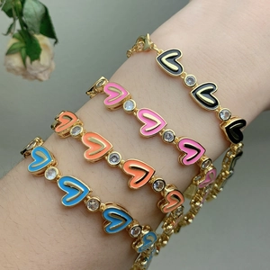 Detail of four colorful zircon heart enamel bracelets in gold finish on a model wrist