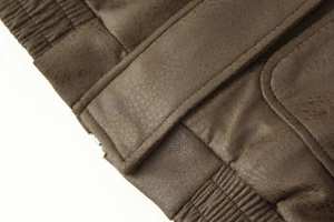 Detail of brown jacket showing ribbed hem and buckle strap on high-quality faux leather