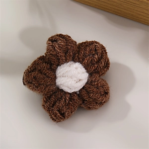 Close-up of handmade knitted flower clip with brown petals and white core detail