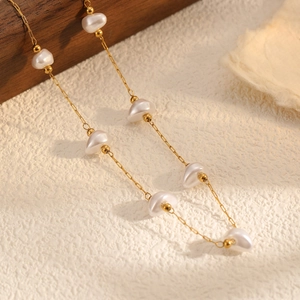 Close-up of gold stainless steel chain with irregular baroque pearls and minimalist texture