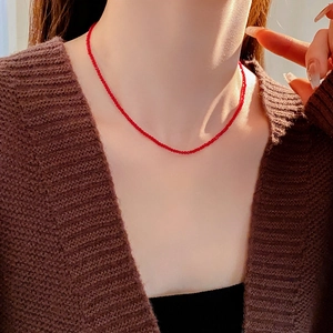 Gros plan d'un collier minimaliste avec petites perles rouges sur la clavicule d'un modèle