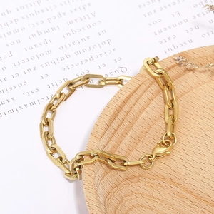 Close-up of golden paperclip chain bracelet on a wooden tray with aesthetic background