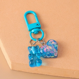 Close-up of blue resin gummy bear and glitter heart charm on metal keychain hook