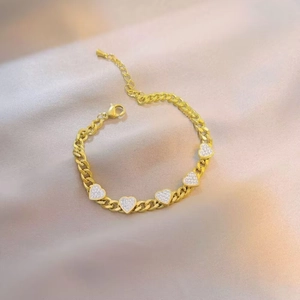 Elegant gold heart Cuban link bracelet with sparkling pavé stones on champagne silk