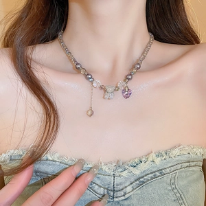 Detail of purple beaded necklace featuring a transparent bear and heart charms on model
