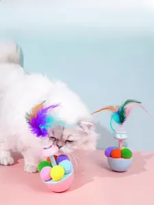 White cat playing with pink Macaron tumbler toy featuring feathers and colorful balls