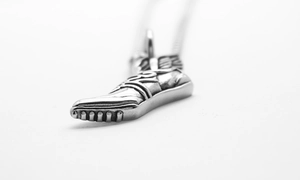 Vue détaillée du pendentif chaussure ailée en métal argenté avec des textures vintage fines