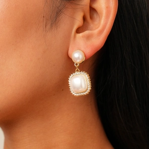 Close-up of a vintage baroque pearl earring with square pendant and pavé zircon accents