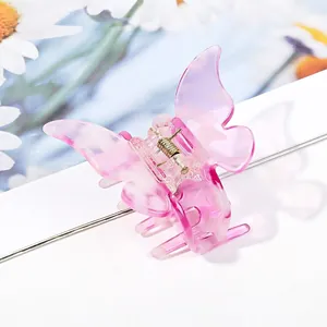 Close-up of a butterfly hair claw clip with pink marble acetate and daisy background