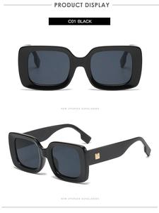 Detail view of square black sunglasses with gold metal rivets and dark grey lenses