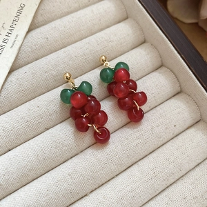 Detailed view of handmade resin grape earrings with red beads and golden needle studs