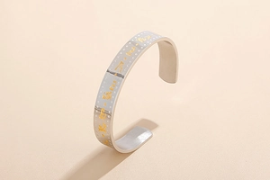 Detail of silver stainless steel cuff bracelet with golden engraved mantra symbols