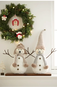 Detailed view of two Christmas snowman plush dolls with knitted hats on a festive mantel