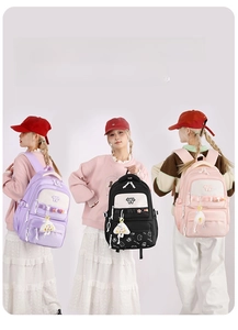 Three school backpacks in purple, black, and pink with cute charms and 'W' logo