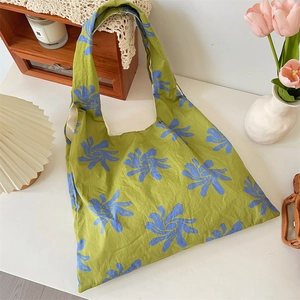 Detailed macro shot of green canvas tote with artistic blue swirl flower patterns