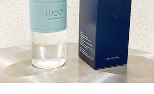 Detail of blue leather sleeve on glass water bottle inside a navy blue gift box