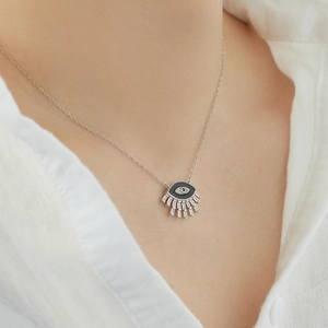 Macro shot of S925 silver eye necklace with blue gemstone and enamel on a model