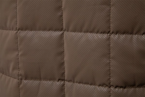 Macro detail of brown quilted jacket fabric with diagonal twill texture and neat stitching