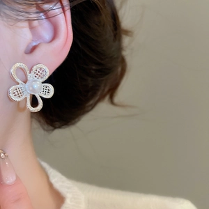 Detailed view of silver hollow flower earrings with pearl on model's ear