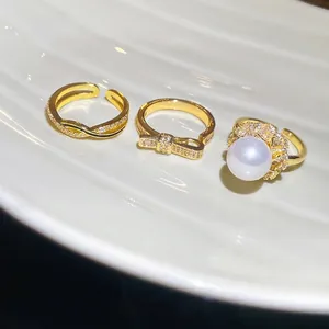 Three-piece gold ring set featuring pearl, bow, and infinity symbols with zircon stones