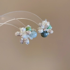 Detail of floral earrings with vintage silver petals, pearls, and green beads in close-up