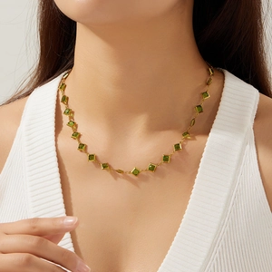 Close-up of gold stainless steel necklace with square green gemstones on a model