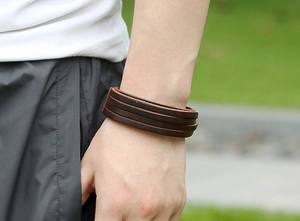 Close-up of a multi-layer brown leather woven bracelet on a man's wrist in natural light