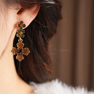 Vue macro de boucles d'oreilles vintage en bronze en forme de croix avec cristaux orange
