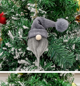 Christmas gnome ornament with gray knit hat and bell hanging on a snowy Christmas tree