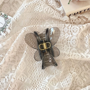Détail d'une pince à cheveux papillon gris translucide avec ressort doré sur dentelle