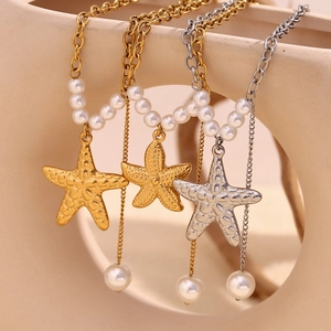 Macro detail of starfish pendants and pearl tassels on 18K gold plated stainless necklaces