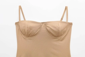 Detail van nude satijnen bodysuit met verstelbare bandjes en voorgevormde cups