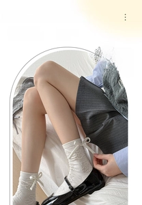 Detail showing white crew socks with embossed bear pattern and ribbon bow decor