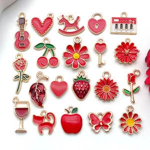 Close-up of red and gold enamel charms including heart, cherry, and floral designs