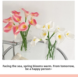 Detail of lifelike pink and white PU calla lilies in modern textured glass vases