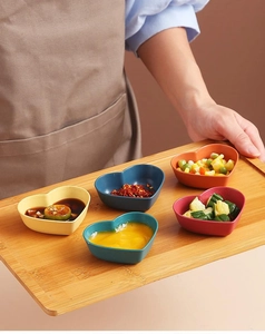 Detailed close-up of colorful heart-shaped sauce bowls arranged on a bamboo serving tray