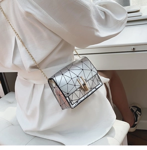 Macro shot of silver geometric puzzle crossbody bag with gold chain strap detail