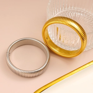 Detalle de brazaletes metálicos elásticos pulidos en oro y plata con rayas horizontales