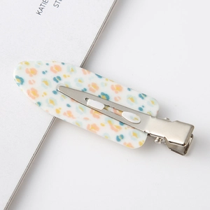 Detail of leaf-shaped hair clip with colorful speckles and silver crocodile base