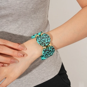 Detail of green leopard print resin bracelet with gold-tone accents on a female wrist