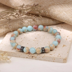 Détail d'un bracelet en perles de pierre naturelle avec espaceurs sur pierre de travertin